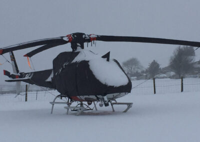 H125 Airbus helicopter with black full covers covered in snow.