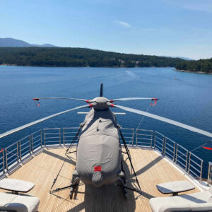 Protection Begins H135 Airbus Helicopter with grey operational cover set on a yacht in sunny weather.