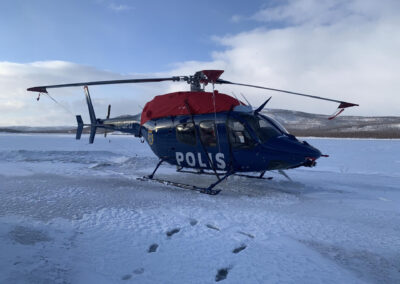 Bell 429 helicopter of the Swedish Police with engine covers and tip socks, on snow-covered ground.